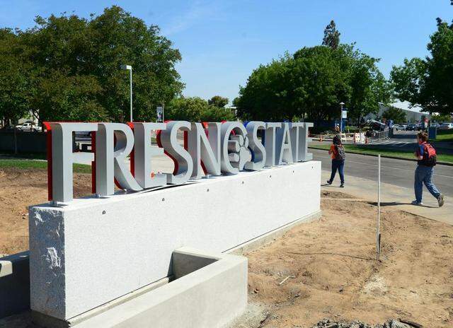 Students walk by a new gateway sign at the entrance to Fresno State at Maple and Shaw avenues, Friday, May 2, 2014. The stone and metal sign lies across from a sculptural element, called a sprout to reflect the school's agriculture, nature, native history, programs and education, made of perforated metal and wood. The signs at Maple and Shaw are the part of the university's Campus Identity and Exterior Wayfinding Comprehensive Sign Program. New gateway signs at the Cedar and Shaw and Cedar and Barstow entrances will be installed later this summer. CRAIG KOHLRUSS